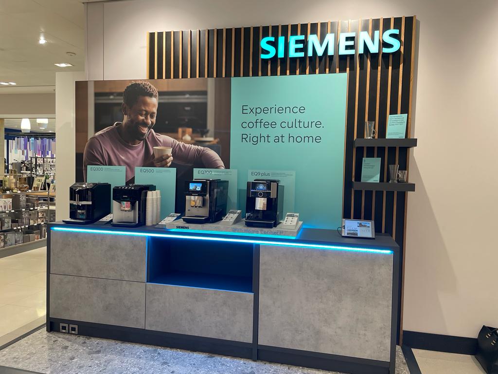Siemens EQ barista display unit detail — dark oak veneer cabinetry with integrated cable management and product plinths